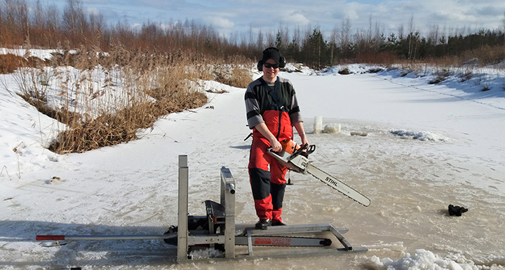 Otto-Ville Sormunen tar ett isprov från en bassäng i Konnunsuo där man behandlar torvvatten. Foto: Mikko Suominen, Aalto-universitetet.