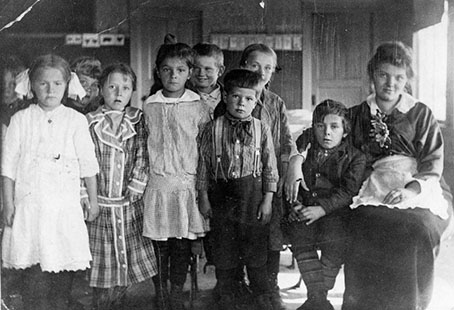 Siirtolaislapsia ja heidän opettajansa mustavalkokuvassa