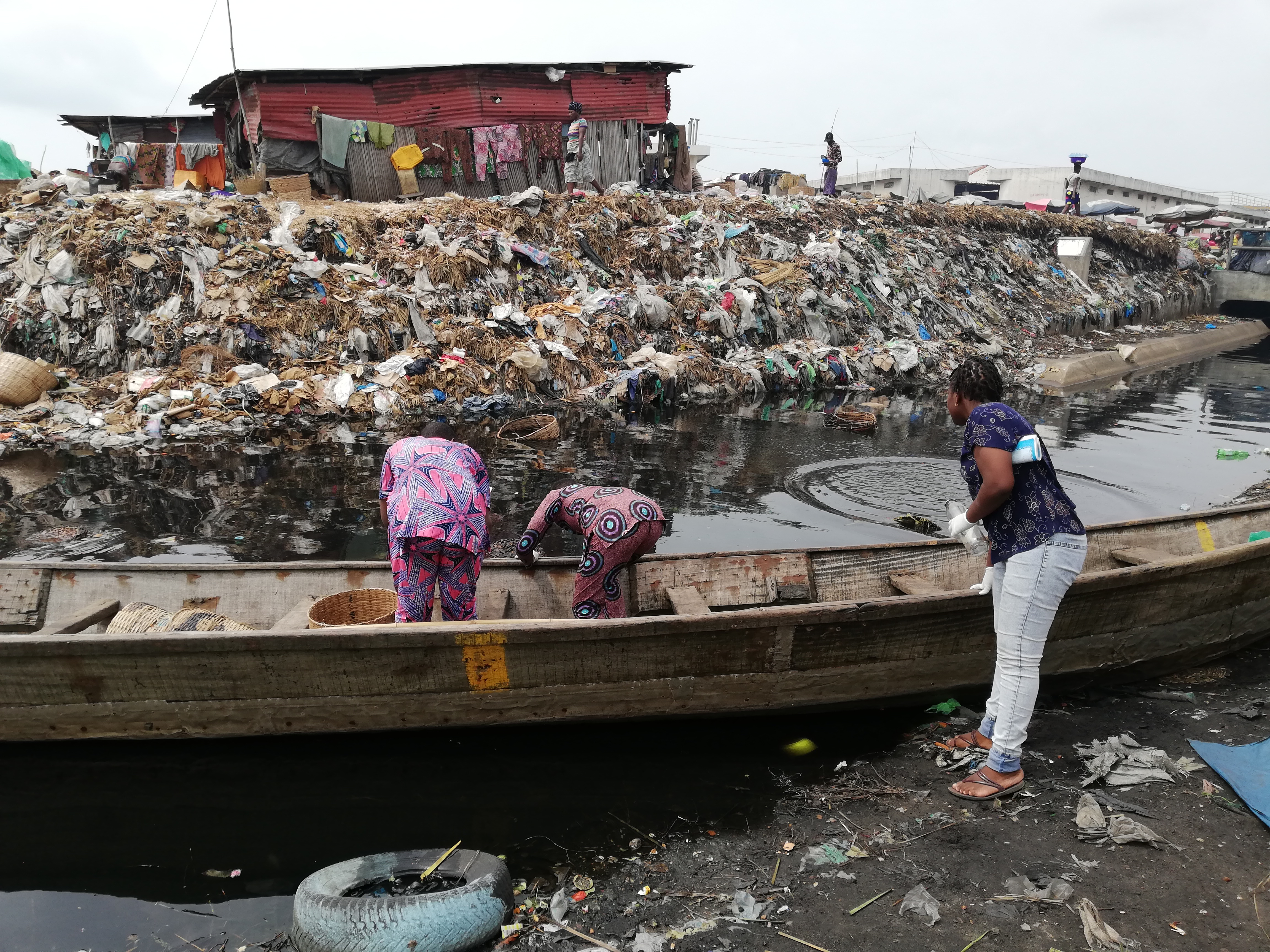 Vesinäytteenottoa kanaalista, joka virtaa Cotonoun pääkauppatorin halki. Sen toisella puolella on kaatopaikka, jonka päällä on asutusta. Kuvassa paikallisia tutkijoita ja opiskelijoita. (Kuva: Kaisa Haukka)